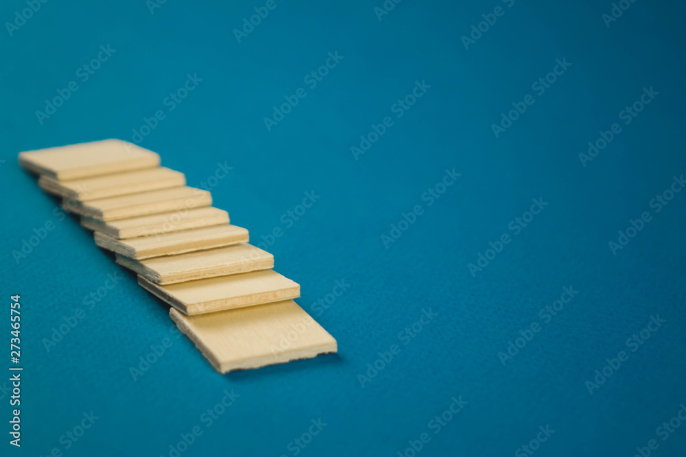 standing on top of each other small wooden blocks on a blue background standing on top of each other small wooden blocks on a blue background