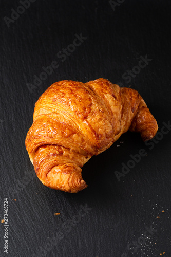 Food concept French croissant on black slate board with copy space