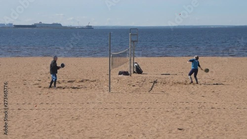 the man and woman on the beach playing tennis