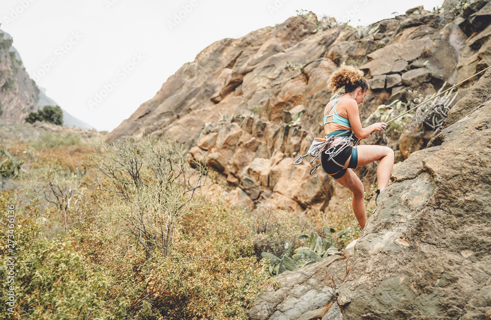 Athletic woman climbing a rock wall - Climber training and performing on a canyon mountain - Concept of extreme sport, people health lifestyle and mountaineering