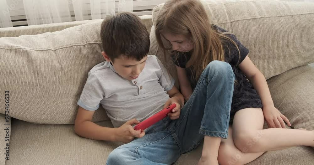 Brother and sister enjoying game together on mobile phone at home Brother and sister enjoying game together on mobile phone at home