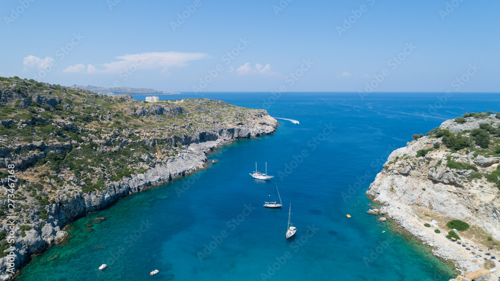 Sailing boats at the beautiful Blue Lagoon at Rhodes Island with blue clear sea water, blue sky and rocks in the water