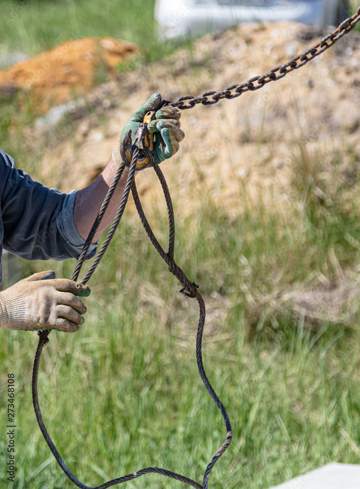 Worker hands with crane hook at construction site at home