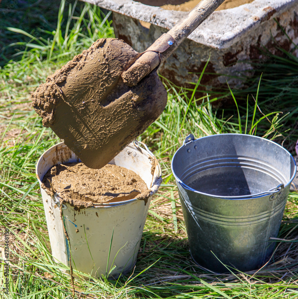 Worker with buckets of concrete at a house construction Worker with buckets of concrete at a house construction