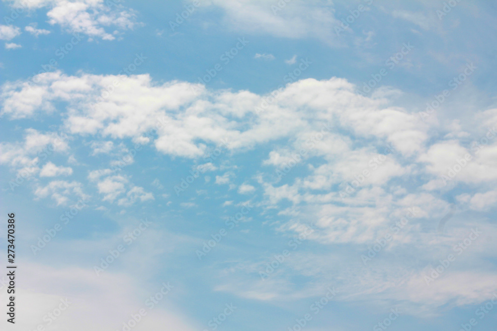 white fluffy clouds slowly float across the blue sky on a blue background