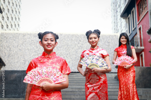 Beautiful Chinese female group in traditional red dress standing, sending a smile to welcome the Chinese New Year.