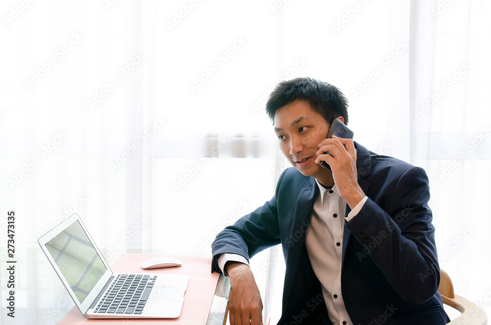 Young Asian Businessman speaking on the phone, looking at computer and thinking to make decision for a deal. Young Asian Businessman speaking on the phone, looking at computer and thinking to make decision for a deal.