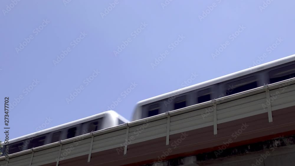Low angle view as a city passenger train passes left to right on an elevated track system.