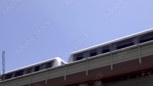 Low angle view as a city passenger train passes left to right on an elevated track system.