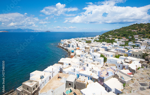 panoramic view from the hill at the Mandrakion city  traditional Greece city whith white houses and blue doors and window shutters between blue sea and green mountains and blue sky in Nisyros Island