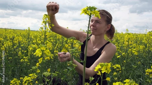 The girl pours earth in her hands, on the field are yellow flowers of rape. Young girl on the nature in the field