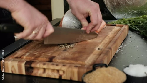 The cook cuts black pepper on the desktop. Cooking red fish on the table close up