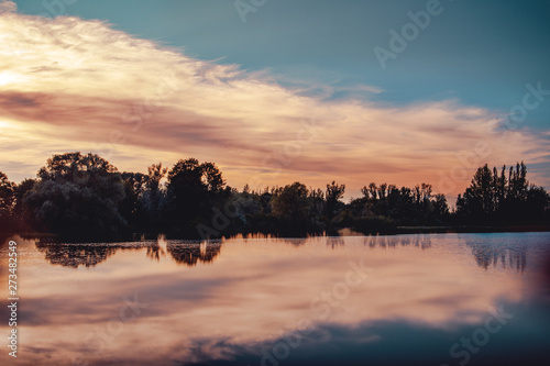 Perfect flat and mirror like water reflection o a lake with colorful sunset clouds. Germany  Braunschweig