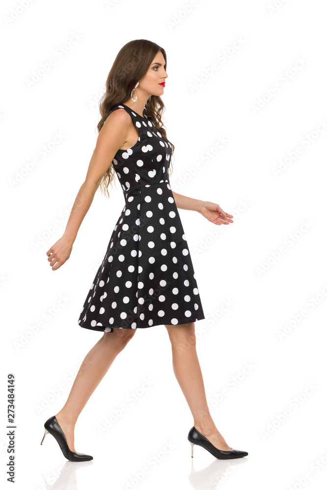 Beautiful Young Woman In Black Dotted Cocktail Dress And High Heels Is Walking Beautiful Young Woman In Black Dotted Cocktail Dress And High Heels Is Walking