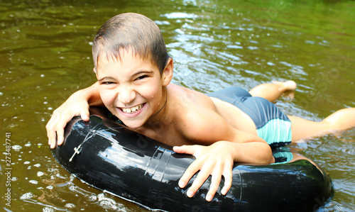 The boy has fun on an inflatable tubing in the river.