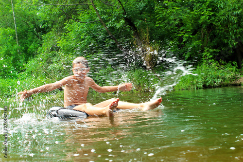 The boy has fun on an inflatable tubing in the river.