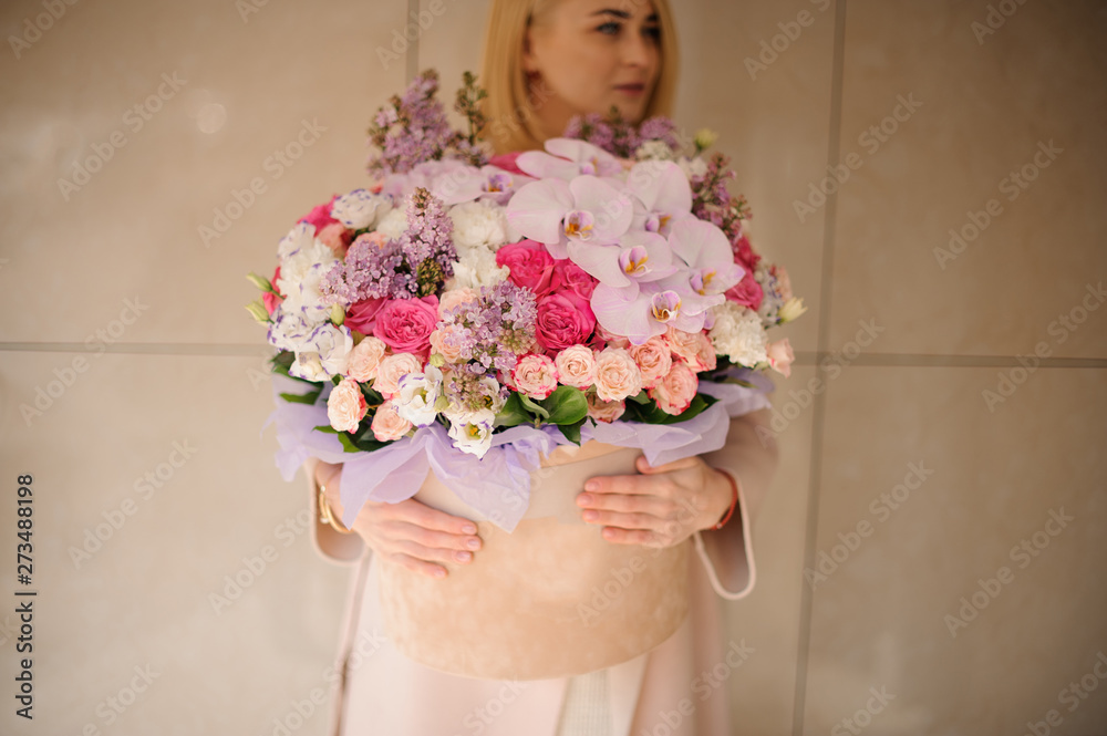 Girl holding a huge spring box of tender multicolored pink flowers