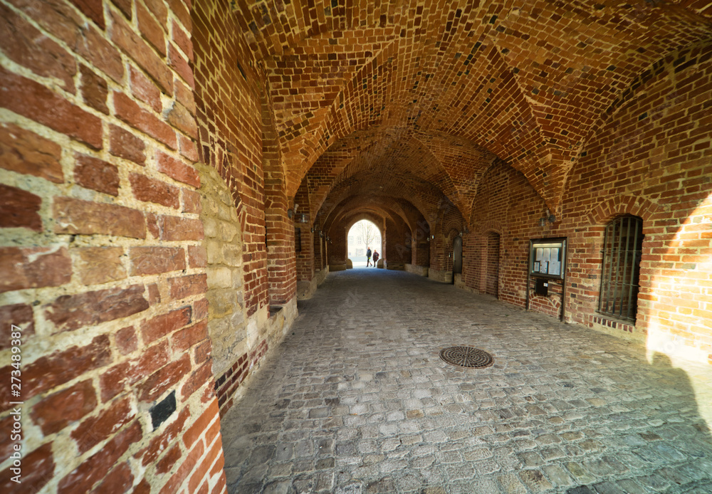 Obraz premium Bricked archway made of red bricks as a passage between the two wings of a medieval castle, architecture