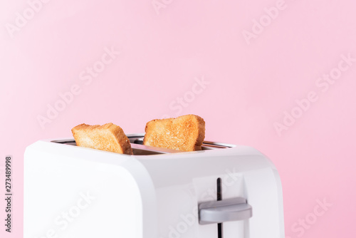 White toaster with  roasted toast bread on pink background, close up