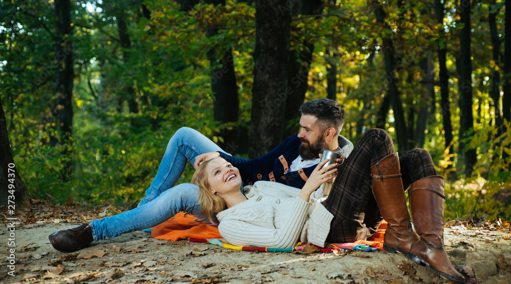 Autumn couple in love hug. Young lovers enjoying each other at a picnic. Woman lying down on the man's leg and having a romantic moment together. Beautiful autumn outside. Couple in loving.