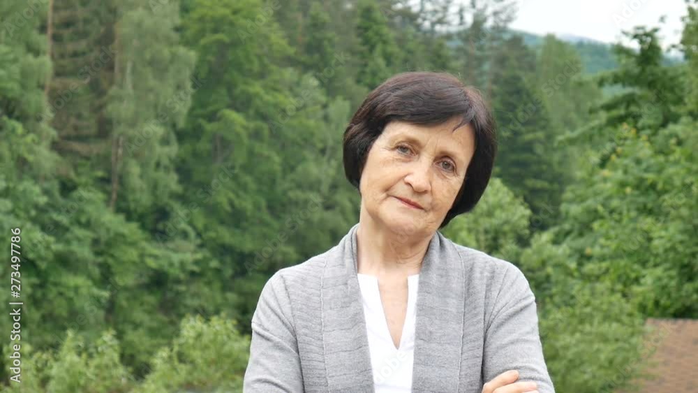 Portrait of a serious pensioner with a reproachful look on the background of mountains in the summer Portrait of a serious pensioner with a reproachful look on the background of mountains in the summer