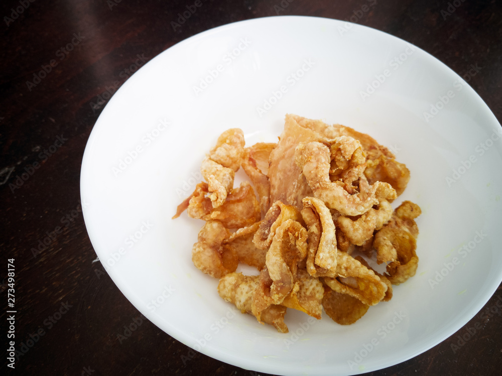 Close up of deep-fried chicken skins in a white bowl. Close up of deep-fried chicken skins in a white bowl.