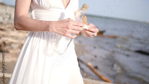 The girl puts her desire in the bottle and lets go into the sea. Bottle on the beach. More videos from this series in my portfolio