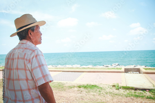 An elderly man wearing a hat looking at the beautiful sea