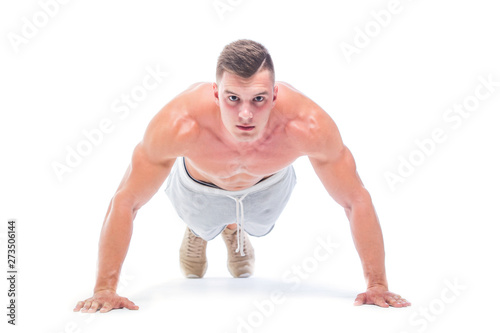 Sports man doing push ups isolated on a white background. Strong Athletic Man - Fitness Model showing his perfect body. © satyrenko