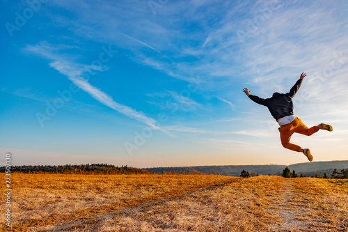 junger Mann feiert seinen Erfolg in der Natur mit Luftsprung