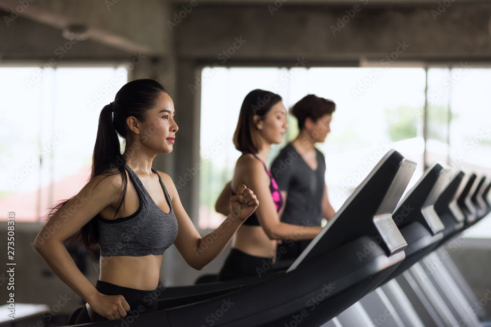 Group of young Asian female and male friends running on treadmills in sport fitness gym. two women and man runn on machine. workout, exercise, training healthy lifestyle.