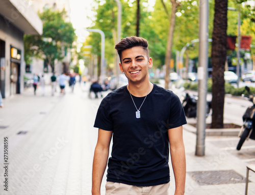 Young fashionable handsome man on the street of modern city. He looks happy and smiling