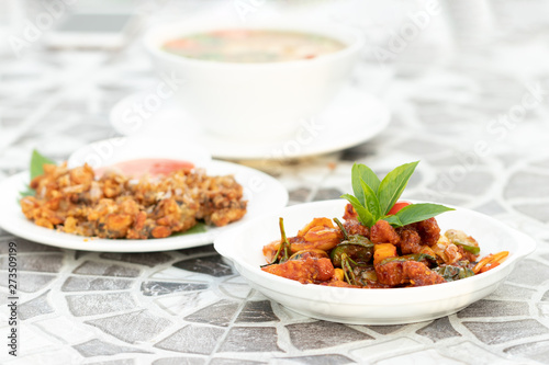 A group of various popular dishes on the table at the restaurant.  The main menu that is Stir fried pork with grilled chilli paste with basil. It has a sweet taste.