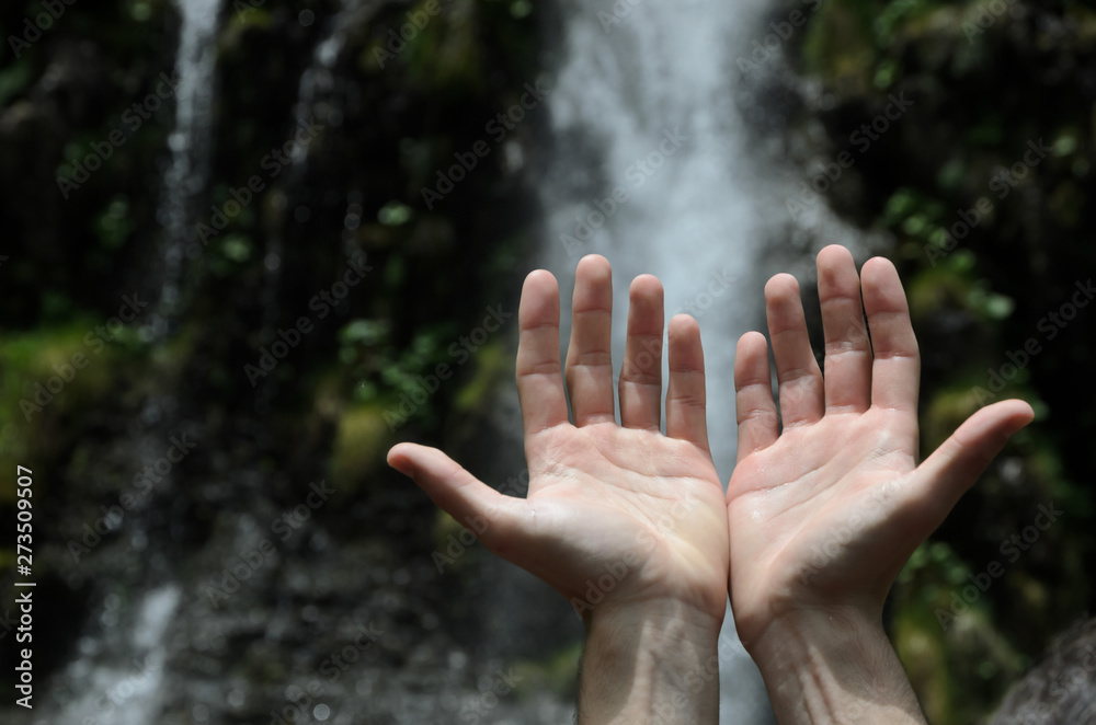 Hands raised towards a waterfall. Hands raised towards a waterfall.