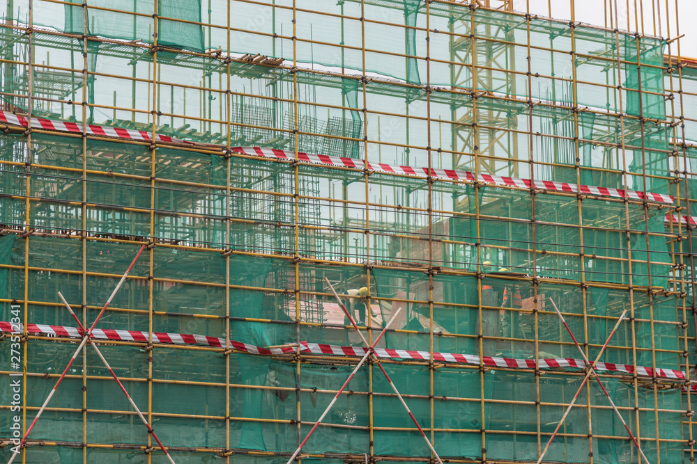Fototapeta premium Several construction workers are under construction in the scaffolding fence of the high-rise building