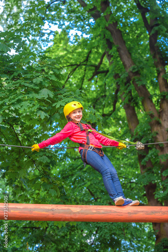 Climber child on training. Child climbing on high rope park. Cargo net climbing and hanging log. Children fun. Portrait of a beautiful kid on a rope park among trees. Cute baby playing.