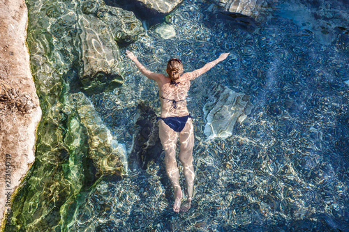 Woman and nature together. Mediterranean leisure and relaxation summer on beach  girl swimming in water. Antique Thermal pool with fragments of ancient columns  Cleopatra s Bath in Pamukkale Turkey