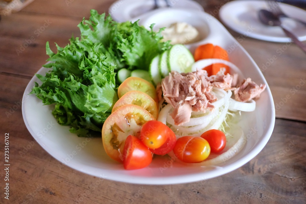 Close up Tuna salad with mixed fresh vegetables and mayonnaise sauce in a big plate on wooden dinning table at the restaurant Close up Tuna salad with mixed fresh vegetables and mayonnaise sauce in a big plate on wooden dinning table at the restaurant