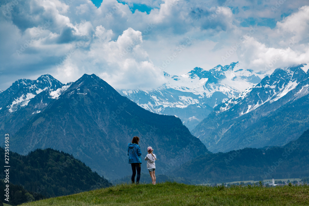 Zwei Mädchen schauen auf die schneebedeckten Alpen