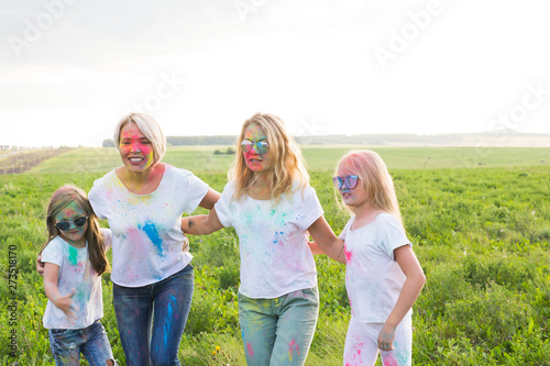 Friendship, Indian holidays and people concept - young women and children dancing on the summer field on festival of holi