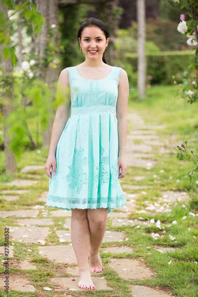Fototapeta premium portrait of young female in dress near roses in a park