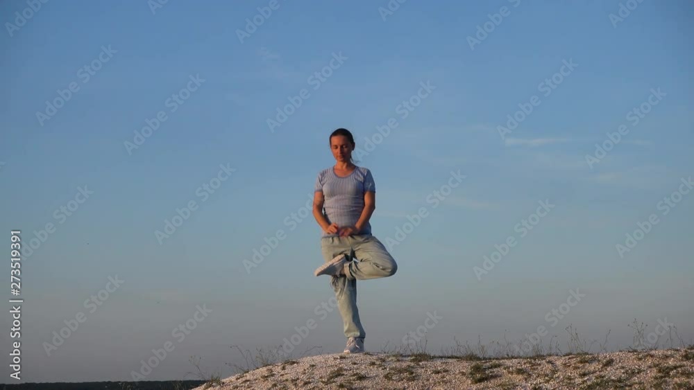 Woman doing tree yoga pose at sunset in nature outdoors Woman doing tree yoga pose at sunset in nature outdoors