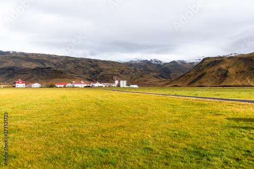 Meadow with a farm at the far edge and mountains in background in Iceland on a sunny autumn day photo