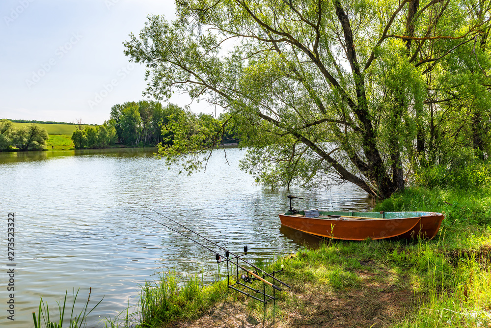Fishing rods and boat by river Fishing rods and boat by river