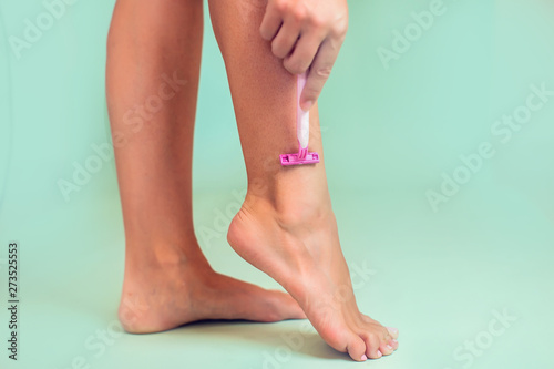 Woman shaves her leg. People, healthcare and beauty concept © Aleksej