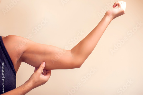 Woman touches her tricep. People, healthcare and beauty concept photo