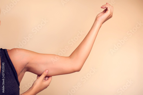 Woman touches her tricep. People, healthcare and beauty concept photo