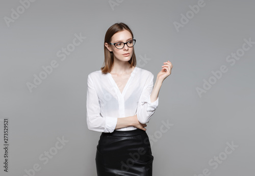 Portrait of the young modern business woman. The strict beautiful thin brunette with the equal business leader of the woman of hair in casual clothes. Gray background.
