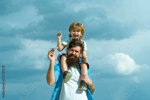 Generation. Father giving son ride on back in park. Father and son building together a paper airplane. Portrait of happy father giving son piggyback ride on his shoulders and looking up.