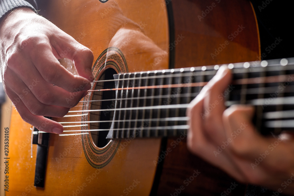 Fototapeta premium adult white guy playing an acoustic guitar. Backlit shooting